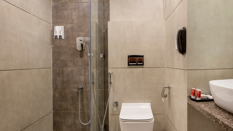 A compact hotel bathroom with a modern toilet and shower area, designed for functionality - SK Lords Inn Ahmedabad