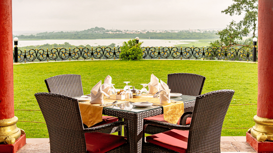 A 4-seater dining table in the outdoors overlooking the vast lawn from the Marble Arch multi-cuisine restaurant at Noor-Us-Sabah Palace, Bhopal.