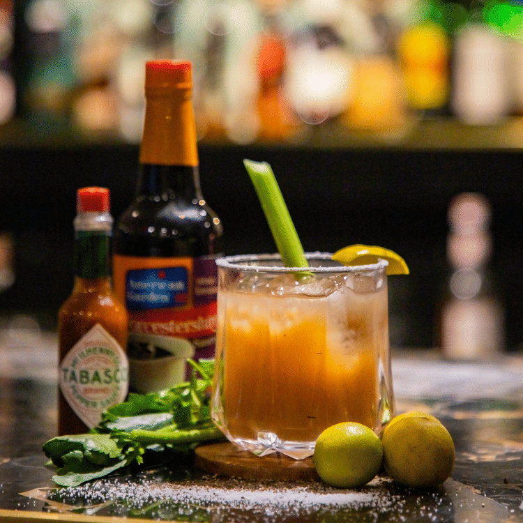 A close up shot foa. table with a drink and tobasco sauce - Karma Lakelands.