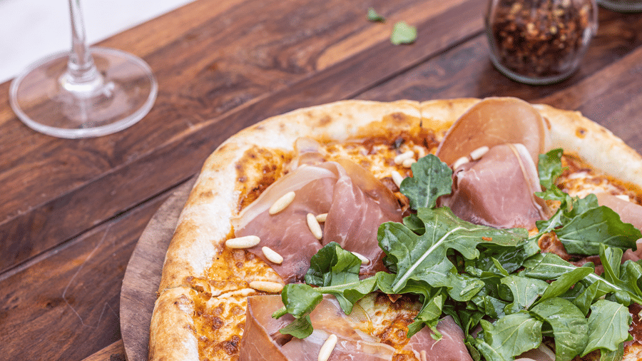 a pizza next to a glass of wine at Rosé