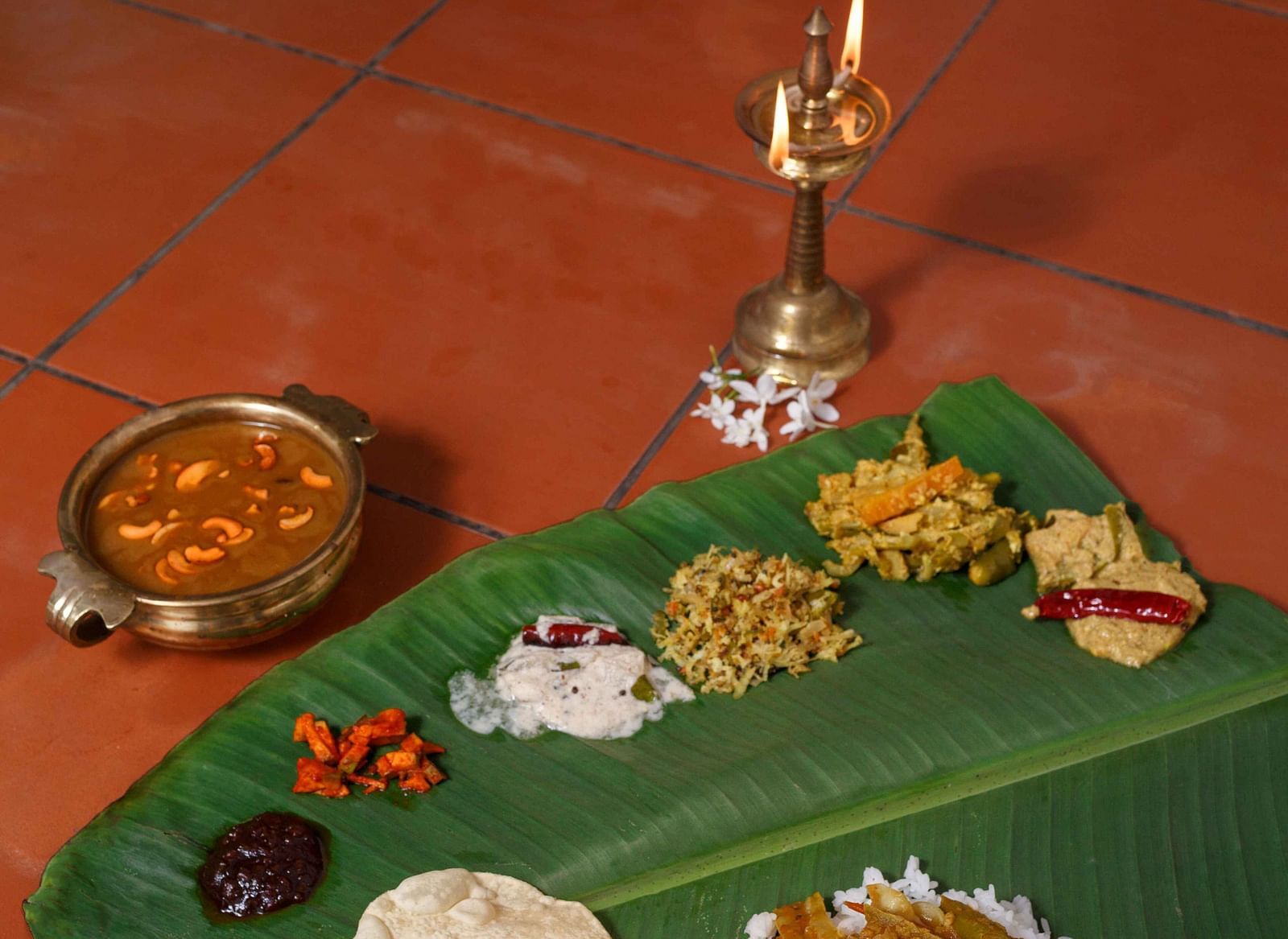 A traditional South Indian meal laid out on a banana leaf, featuring various dishes and accompaniments.