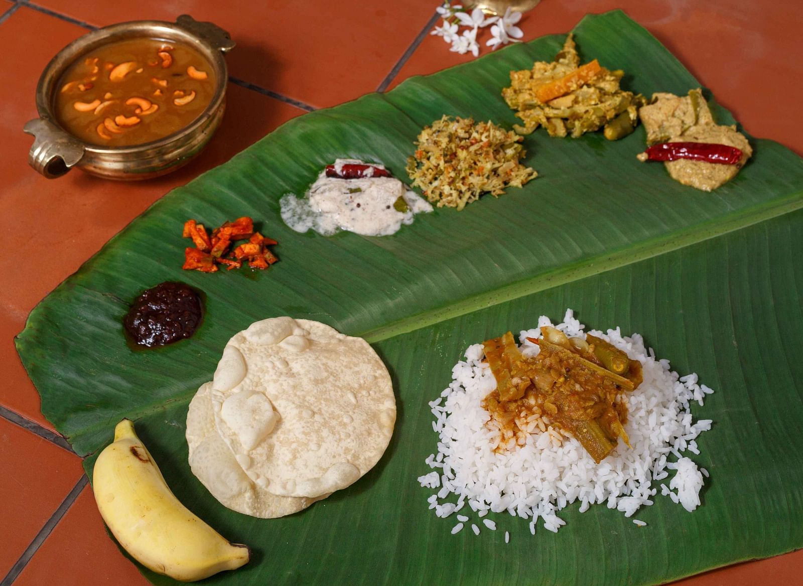 A traditional South Indian meal laid out on a banana leaf, featuring various dishes and accompaniments.