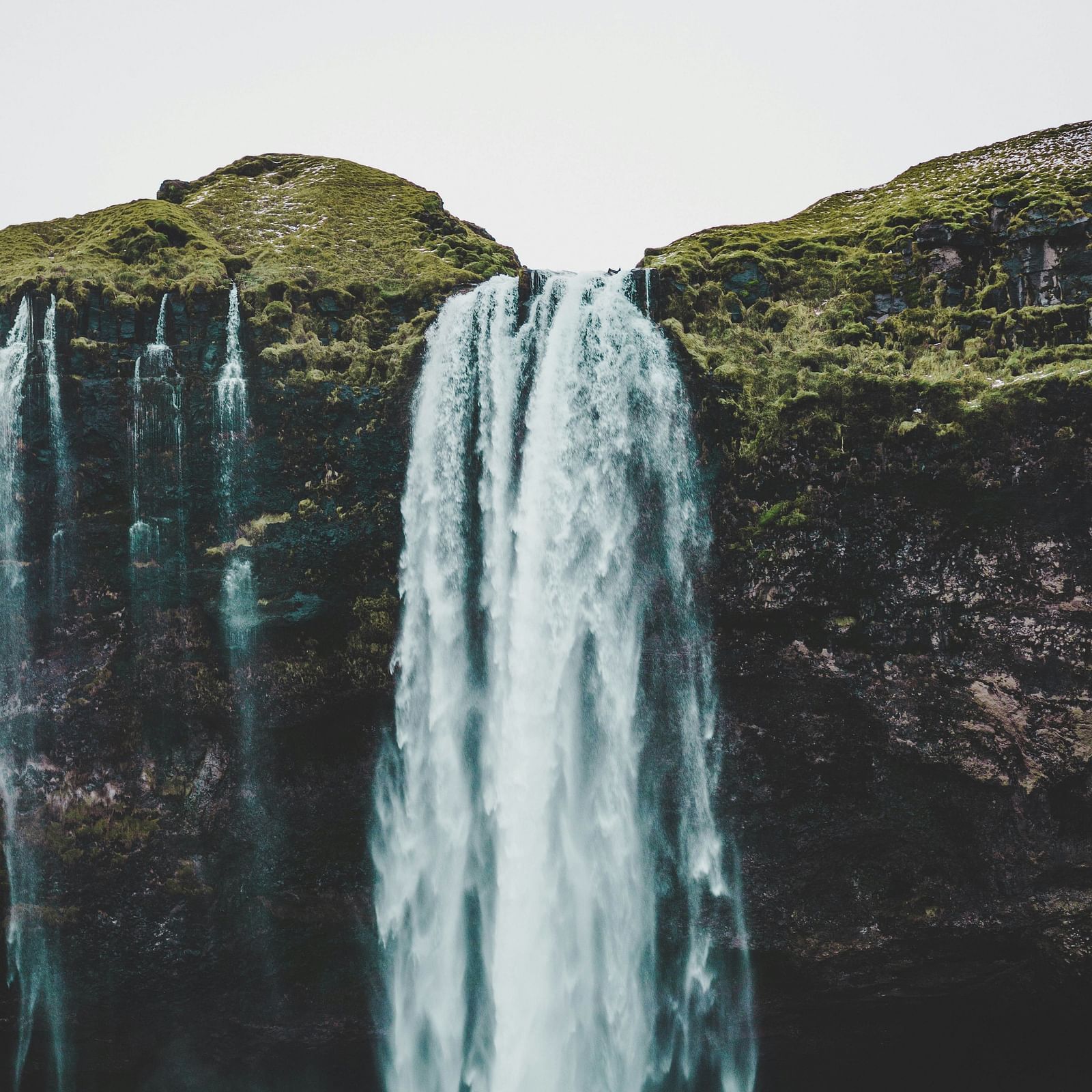 A majestic waterfall cascading down a rocky cliff with lush greenery, creating a powerful and serene natural landscape.