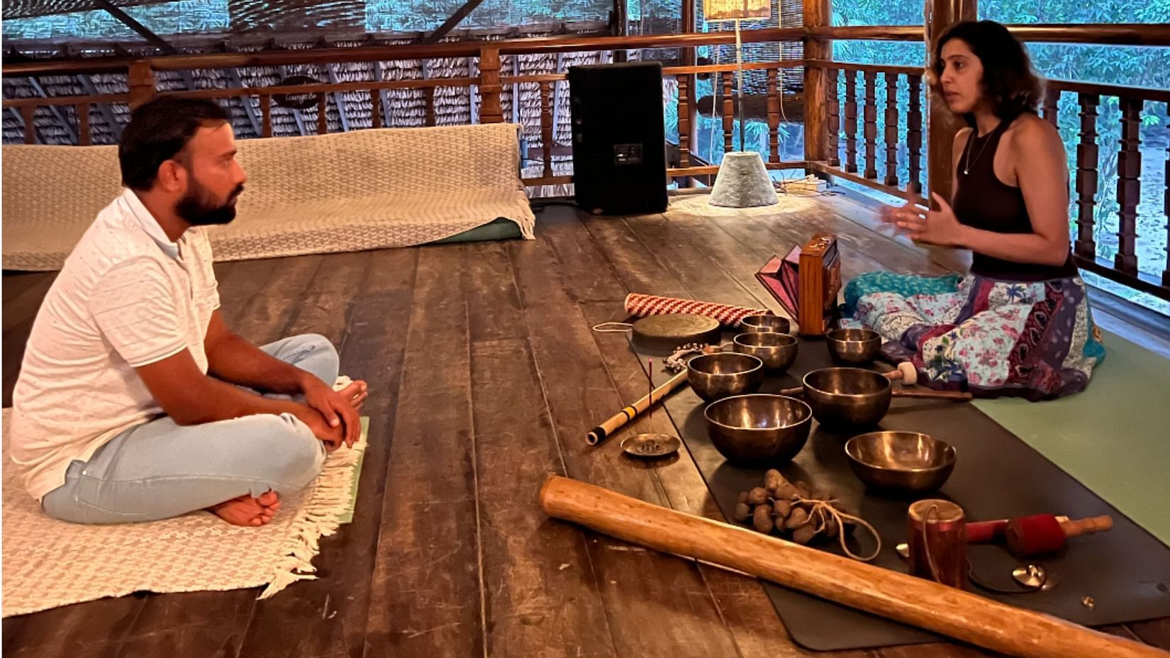 A woman guiding a man through a sound meditation session.