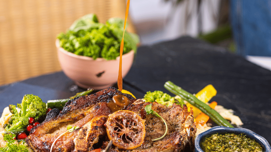 sauce being poured over a meat dish at Rosé