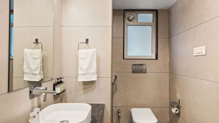 Modern bathroom with a wash basin, water closet, a towel racket, and a window at Mayur Retreat
