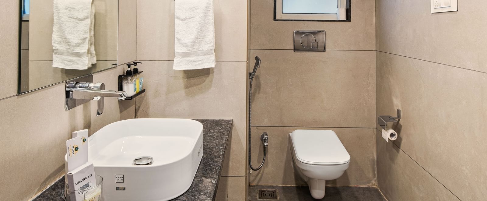 Modern bathroom with a wash basin, water closet, a towel racket, and a window at Mayur Retreat