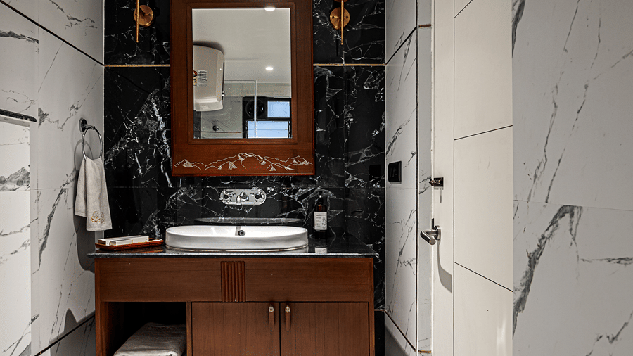 The modern bathroom at Hotel Sonar Bangla, Darjeeling with marble-effect walls and a dark wood vanity unit.