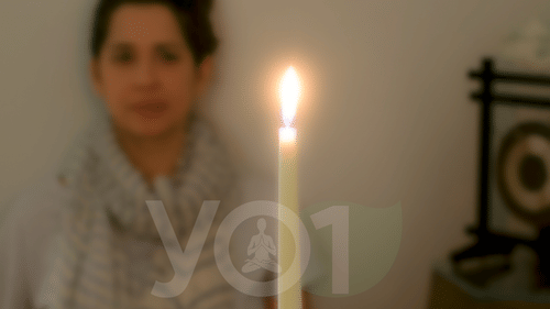 Woman practicing Trataka meditation, gazing steadily at a candle flame to enhance focus, calm the mind, and improve concentration at YO1 Longevity & Health Resorts