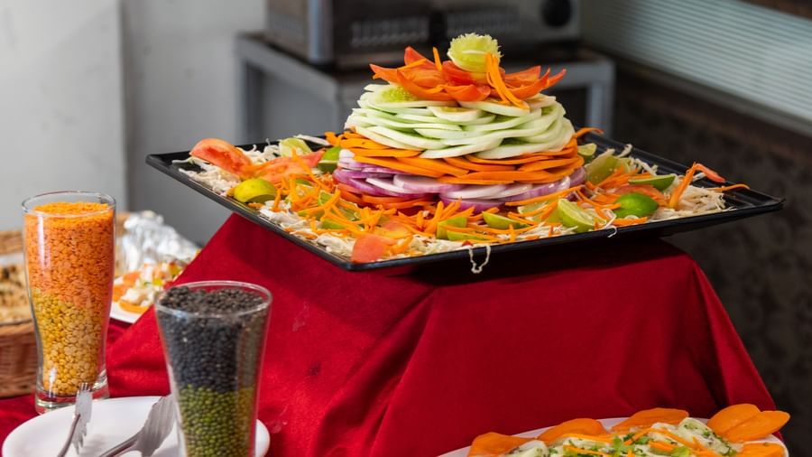 A dish displayed on a table with red cloth at The Darbar Restaurant with side dishes.