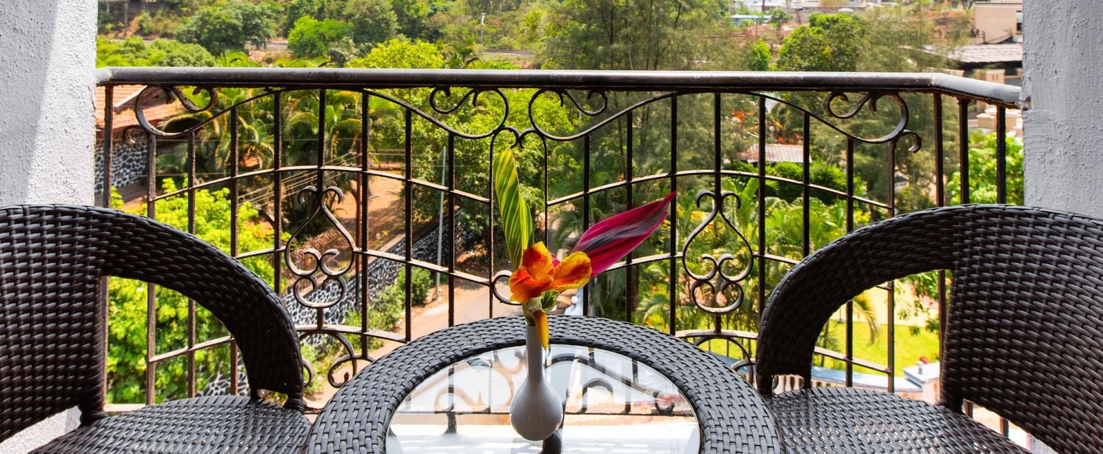 Balcony view from Mayur Retreat with a table for two overlooking lush greenery.