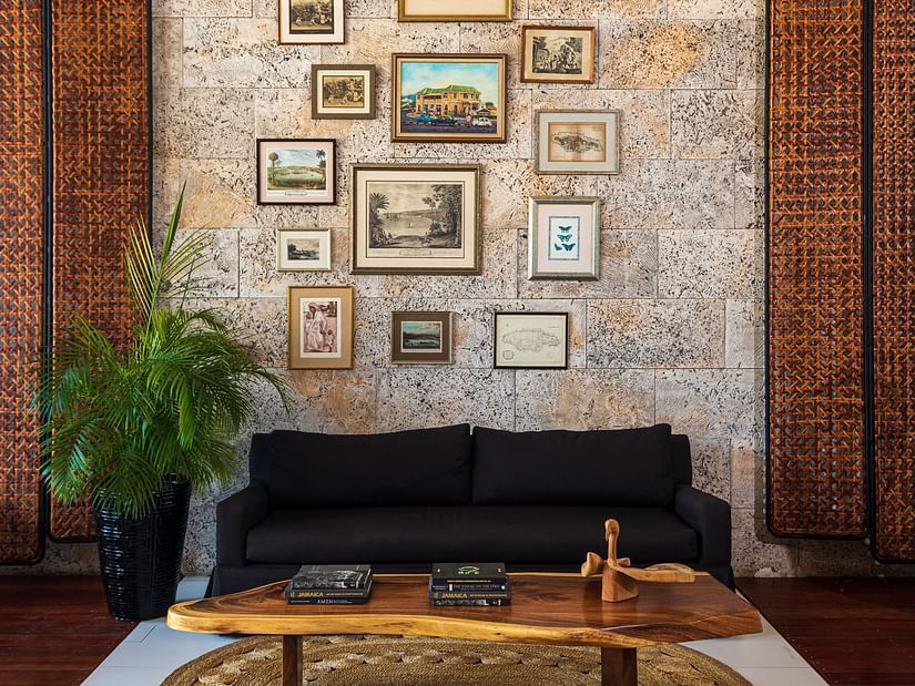 An image of a hotel lobby with a black couch and teapoy placed in front of a wall with pictures - S Hotel Montego Bay, Jamaica