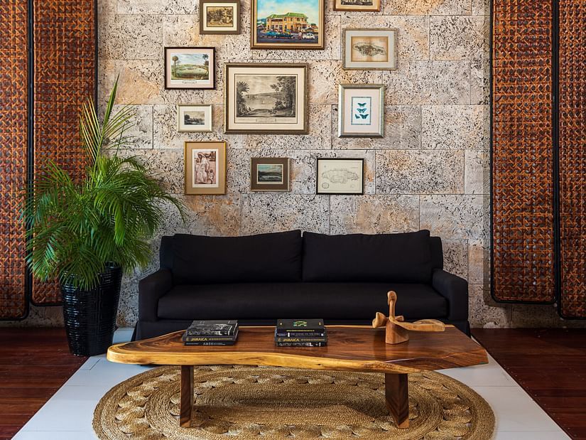 An image of a hotel lobby with a black couch and teapoy placed in front of a wall with pictures - S Hotel Montego Bay, Jamaica
