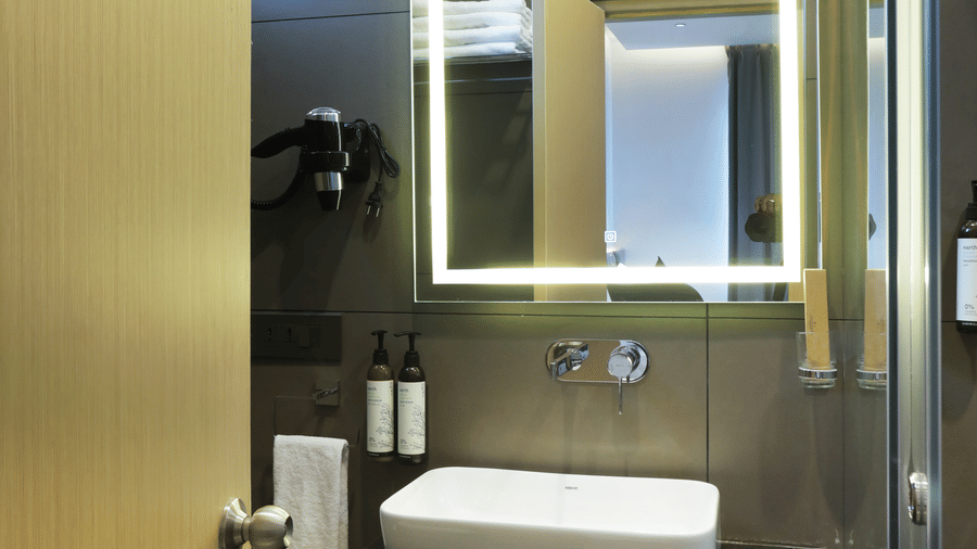 Backlit vanity mirror above sleek washbasin in Luxury Suite bathroom at Hotel Kyzen HiTech City – Your Zenly Stay.