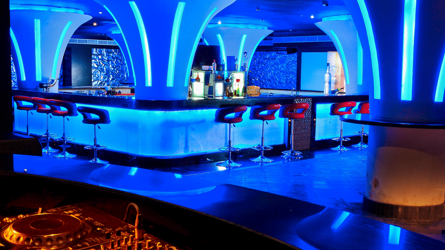 Ska bar Discotheque with neon lights featuring a bar counter and several chairs around it at Ocean Spray Puducherry.