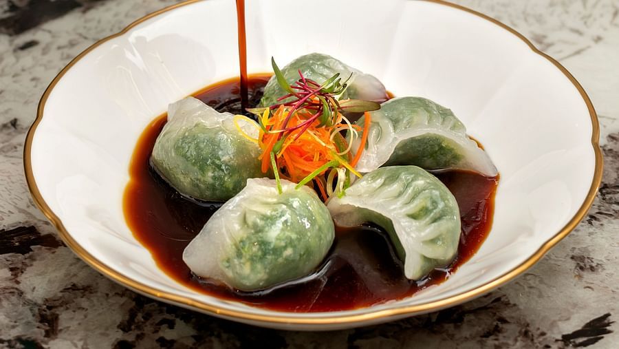 image of a plate of dim sums served with a dark coloured sauce poured over at the jade - The Claridges New Delhi