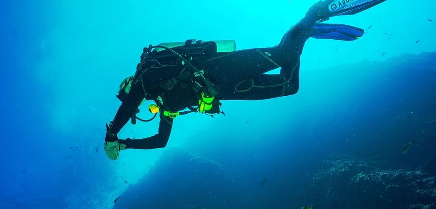 divers exploring the water with the sun's rays shining down through the water
