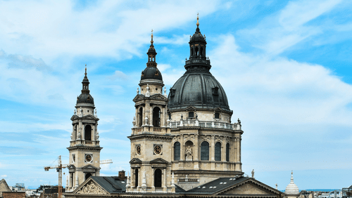 A far out view of a basilica with high towers and trees in the foreground
