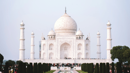 A far out view of Taj Mahal with a waterbody reflecting the building in view..