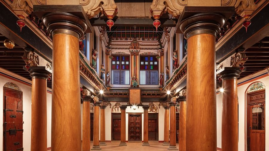 Spacious traditional hall with polished wooden columns and a vibrant array of cultural decorations at Chidambara Vilas Resort