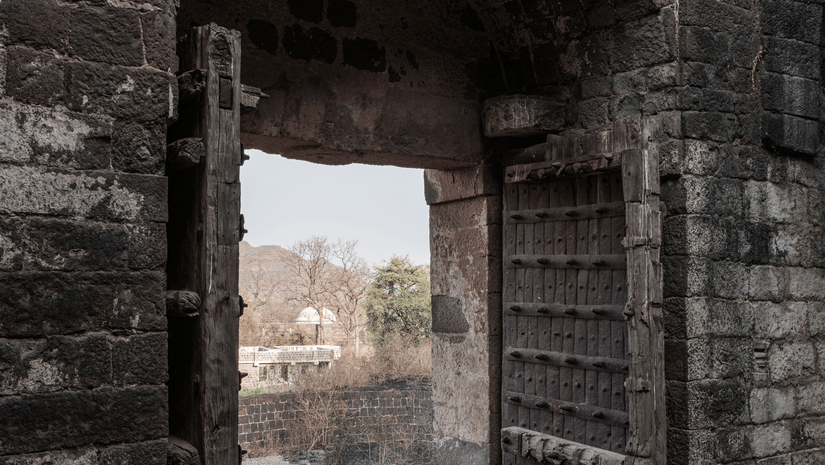 A historic stone gateway with wooden doors seen from the inside