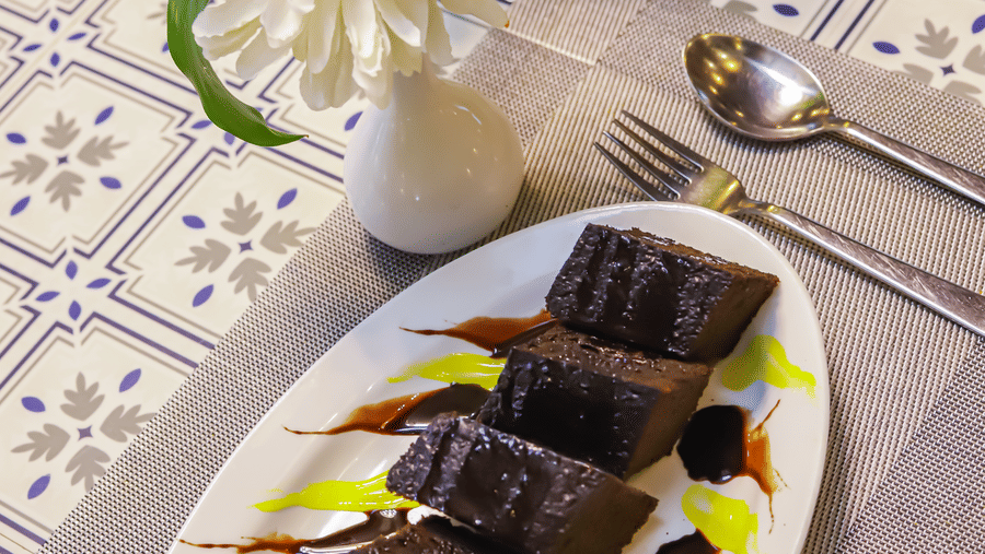 An oval plate with dessert sits on a table with a floral arrangement at Vedikant Resorts The Mallard Corbett.
