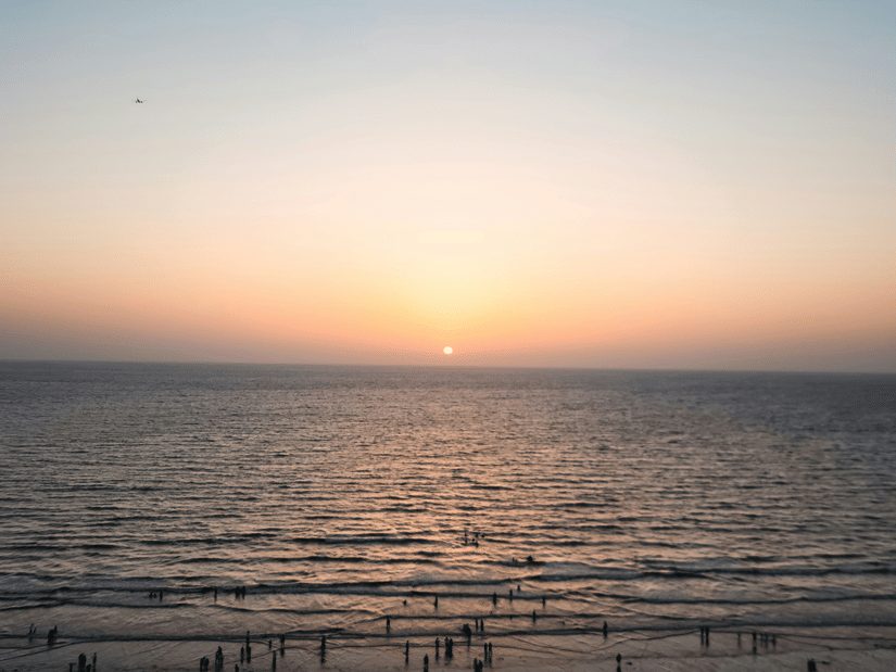 Juhu Beach, a beautiful sunset beach (Mumbai), during sunset with numerous people on the shoreline and the Arabian Sea also in view.
