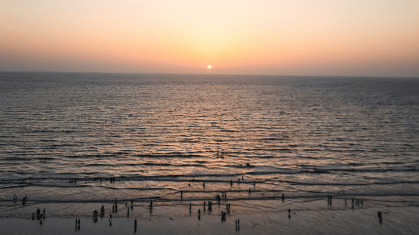Juhu Beach, a beautiful sunset beach, during sunset with numerous people on the shoreline and the Arabian Sea also in view.