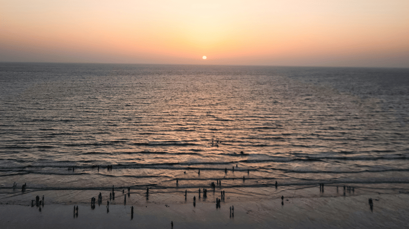 Juhu Beach, a beautiful sunset beach, during sunset with numerous people on the shoreline and the Arabian Sea also in view.