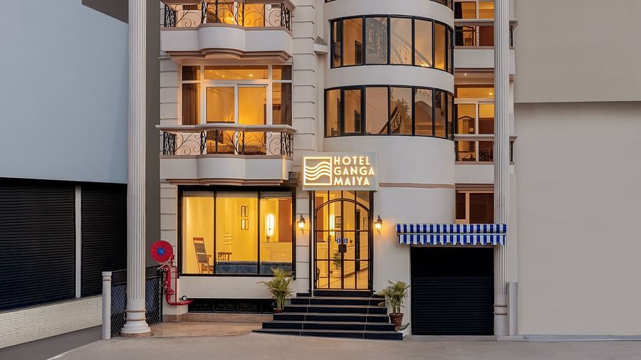 Facade view of Hotel Ganga Maiya, with warm lighting radiating from inside, set against a cloudy sky | Hotel Ganga Maiya