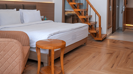 A loft suite with a queen size bed on the lower floor and wooden stairs leading up to an upper level at Ramada by Wyndham Mussoorie Mall Road.