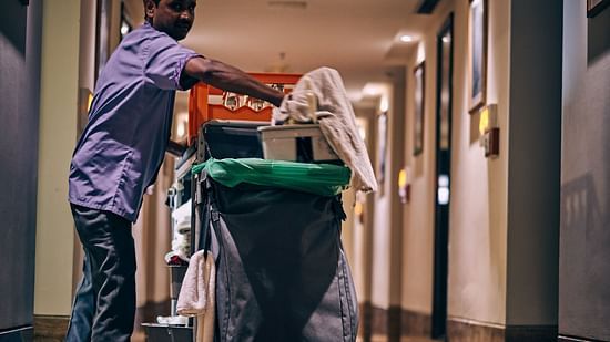 A person carrying a dustbin in the corridor