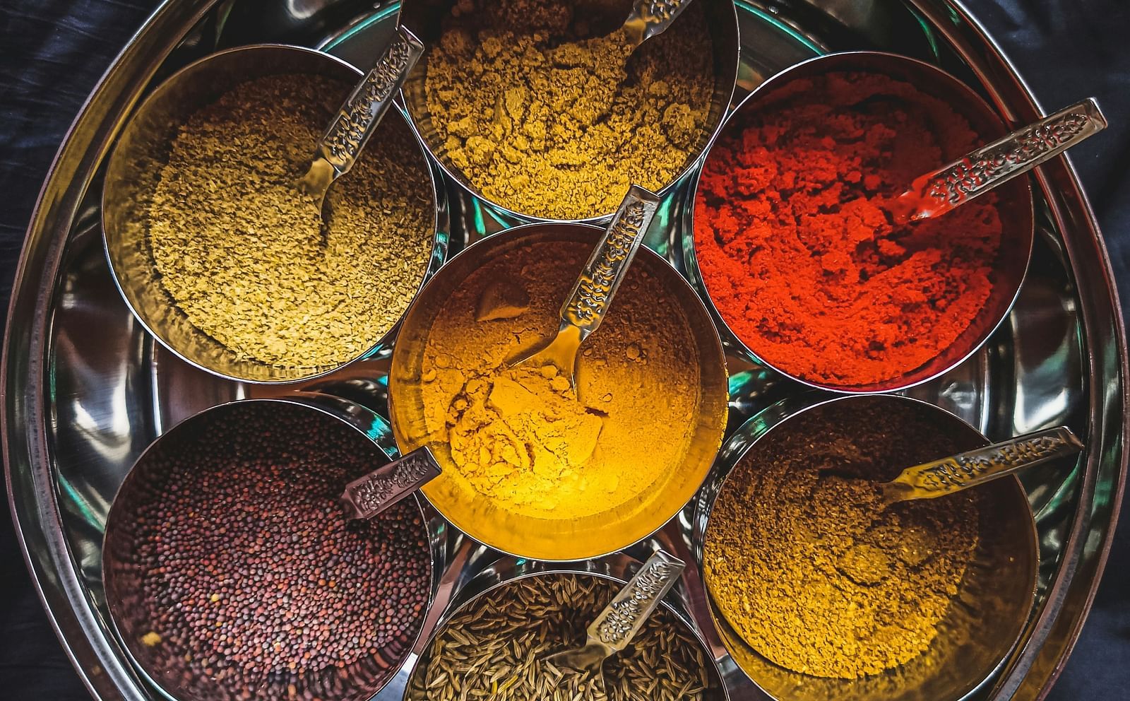 An aerial view of the many spices in a steel bowl that are used for cooking.