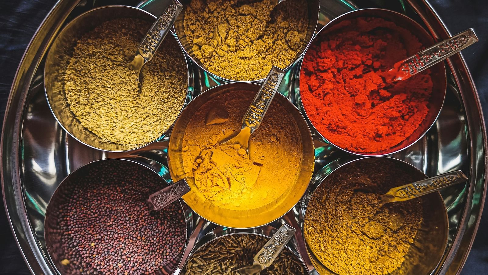 An aerial view of the many spices in a steel bowl that are used for cooking.