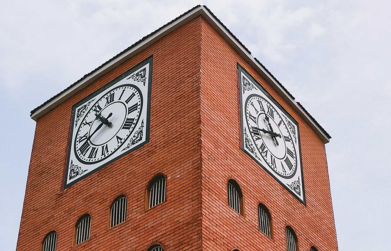 Picture of a tall, brick clock tower captured in day light.