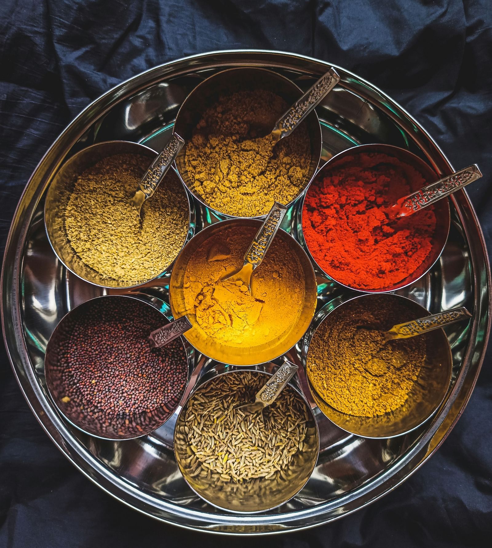 An aerial view of the many spices in a steel bowl that are used for cooking.