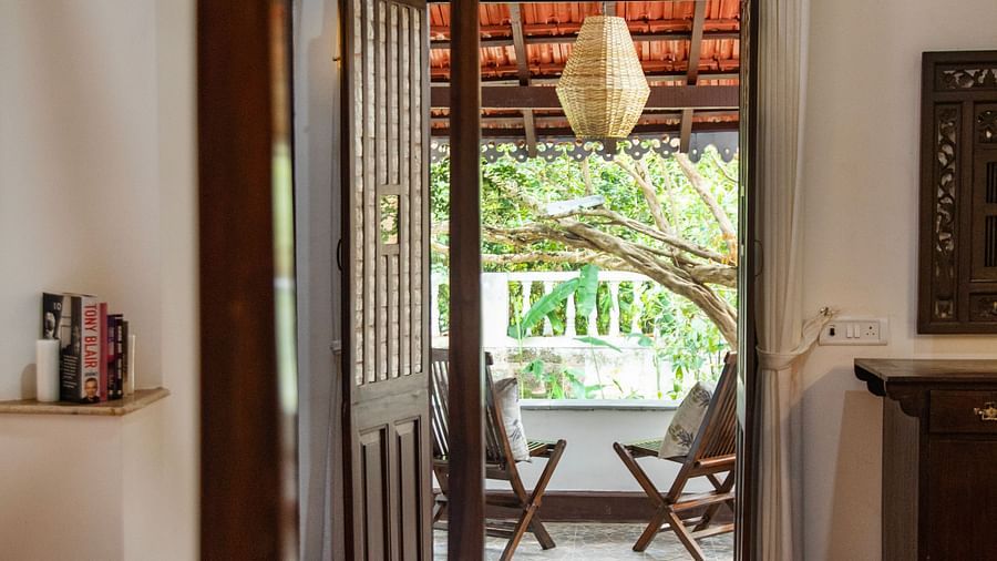 bed with view of greenery through open wooden door  @ Lamrin Ucassaim Hotel, Goa