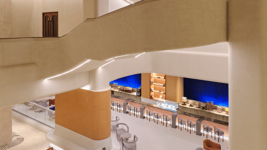 Café with hanging staircase at Swosti Premium Beach Resorts, Puri, with a retail area visible on the ground floor.