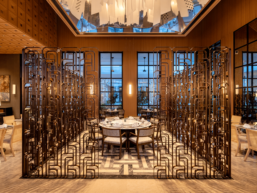 Front view of Chin Chin restaurant at The Residency Signature Madurai with decorative metal partitions, pendant lighting, and warm ambient lighting.