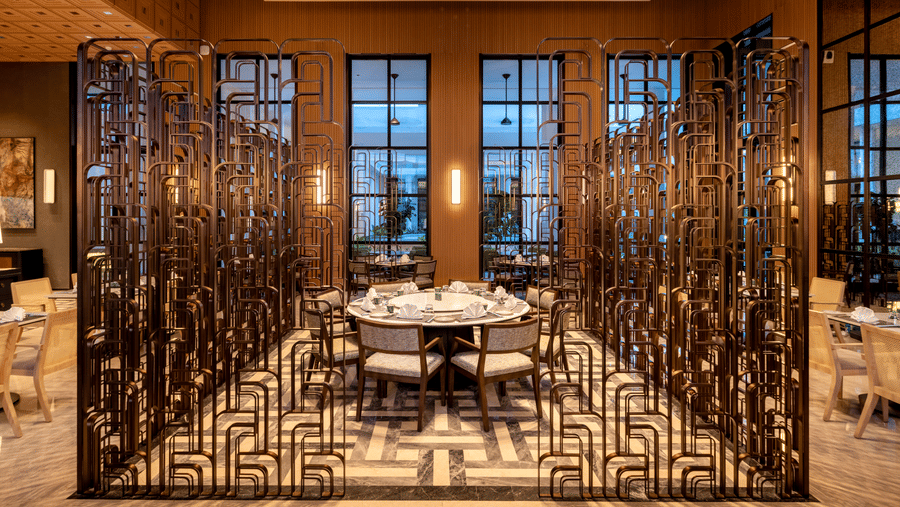 Front view of Chin Chin restaurant at The Residency Signature Madurai with decorative metal partitions, pendant lighting, and warm ambient lighting.