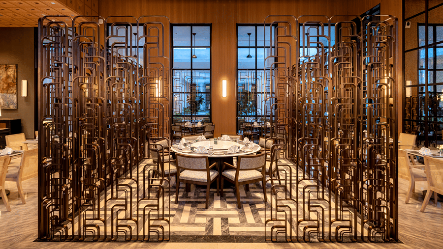 Front view of Chin Chin restaurant at The Residency Signature Madurai with decorative metal partitions, pendant lighting, and warm ambient lighting.
