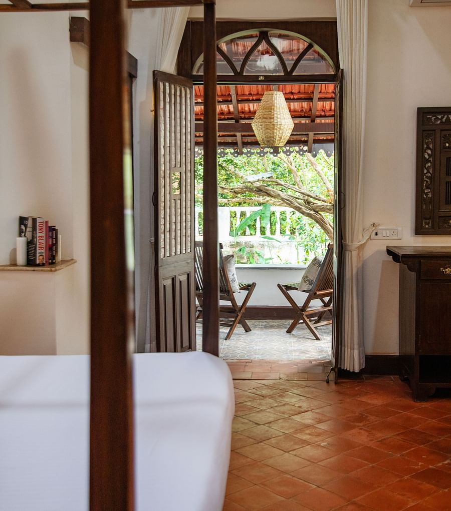 bed with view of greenery through open wooden door  @ Lamrin Ucassaim Hotel, Goa