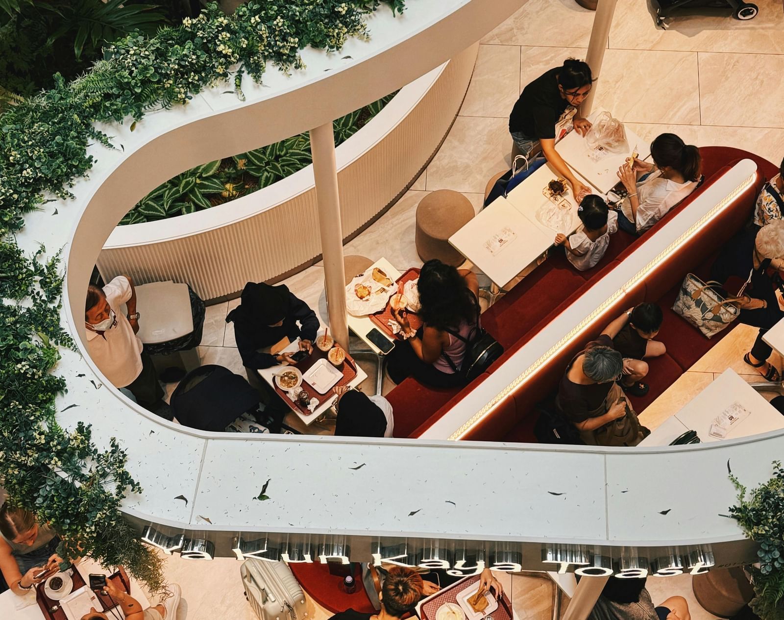 An aerial view of a vibrant outdoor setting with people gathered around tables and lush greenery.