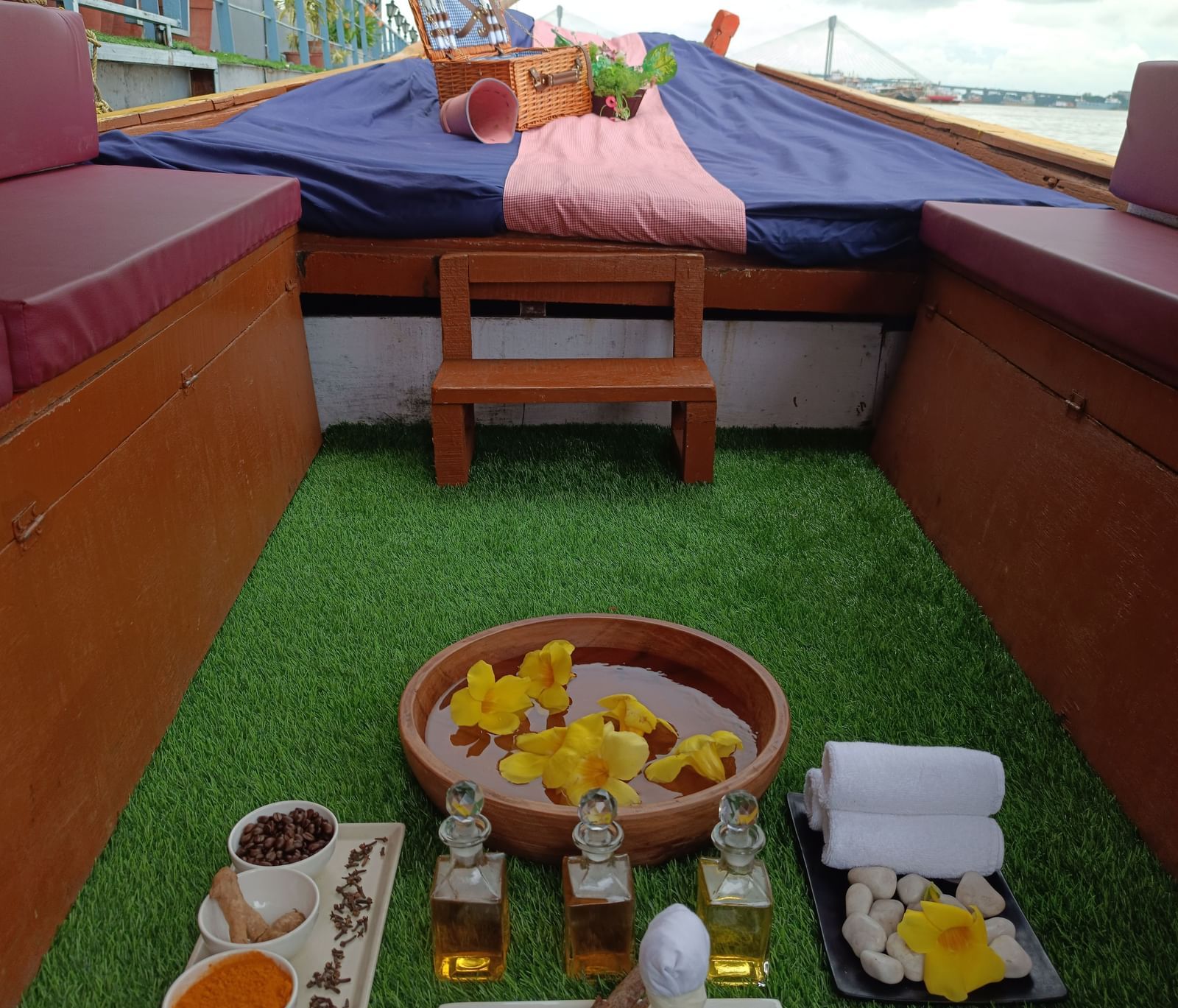 A close-up view of a green astroturf area on the deck of Polo Floatel Kolkata, showing a table with small bowls and glasses filled with sauces and drinks.