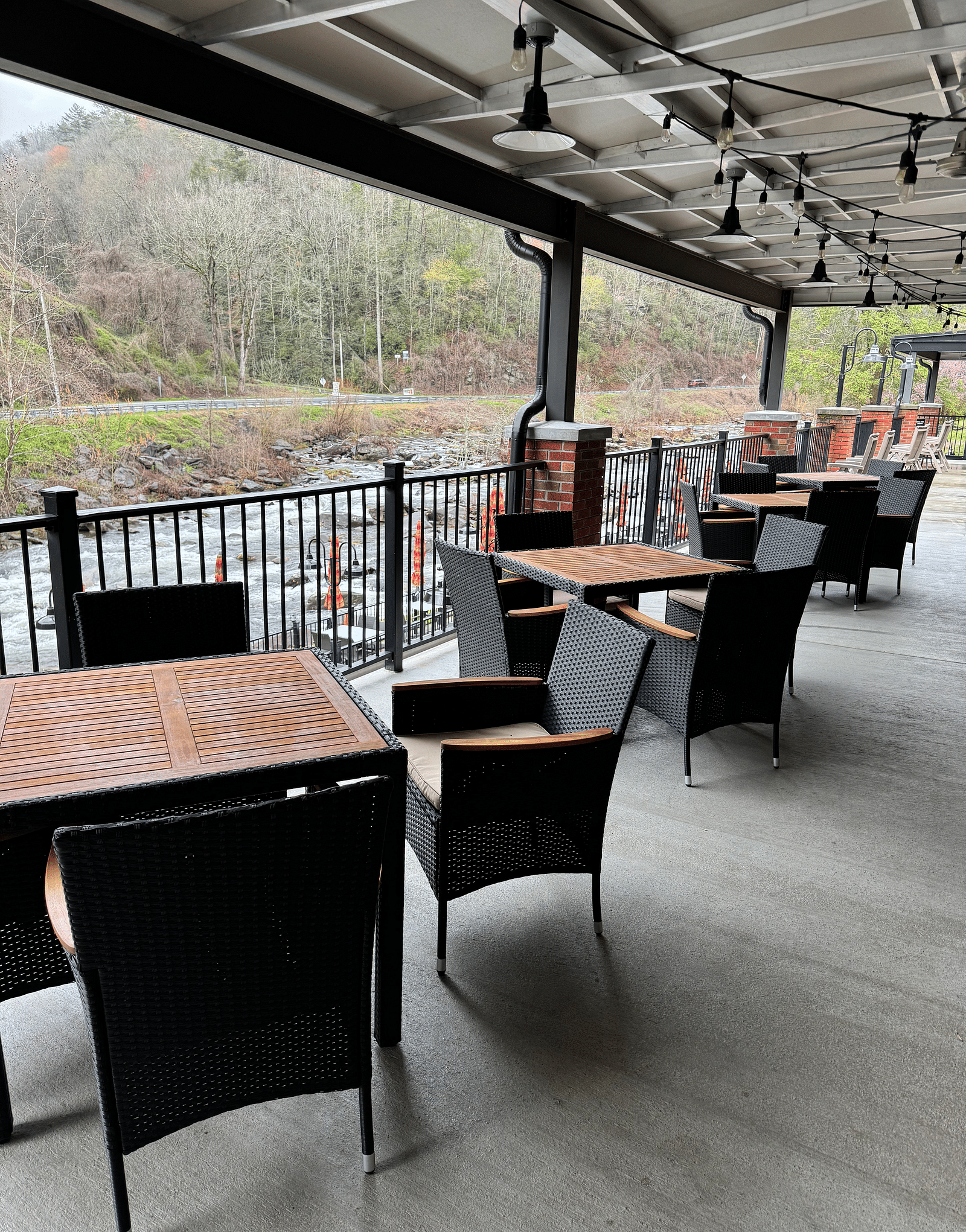 an outdoor dining area with tin roofs above it overlooking the beautiful Cheaoh river on a misty day - Historic Tapoco Lodge