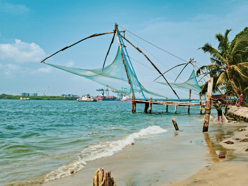 A traditional Chinese fishing net (Cheena Vala) standing over the water on a beach in Fort Kochi.