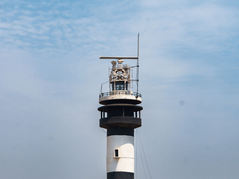 Black and white lighthouse standing tall against a clear blue sky.