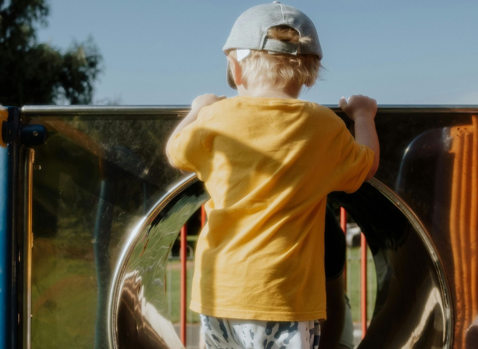 A young child, seen from the back, standing at the entrance of a tunnel slide.