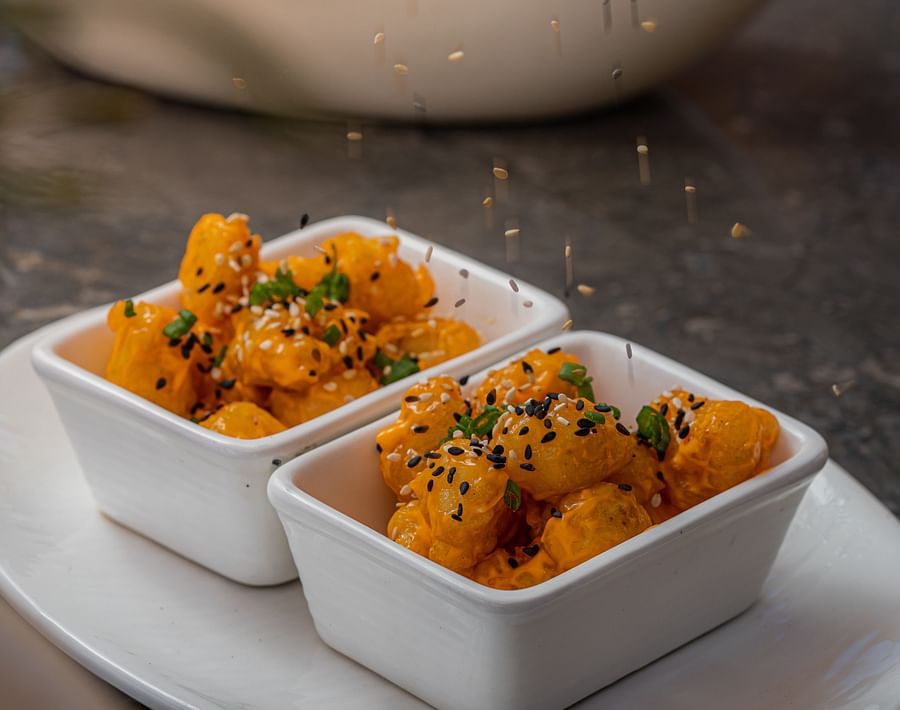 alt-text two rectangular bowls kept on a plate with a colourful potato dish