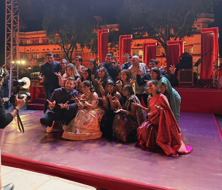 A group gathered on a brightly lit event stage at night with vibrant stage lighting at Umaid Palace.